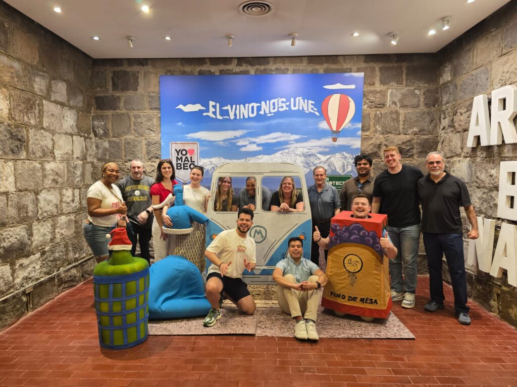 group of MSMIT students and Stefano Grazioli pose in front of a sign that reads El Vino Nos Une
