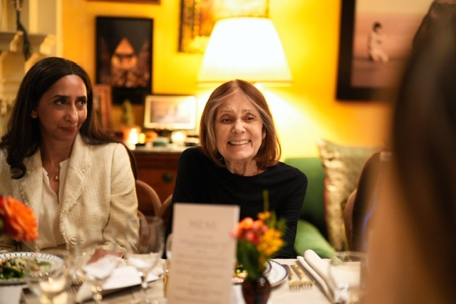 Gloria Steinem sitting with dinner guests