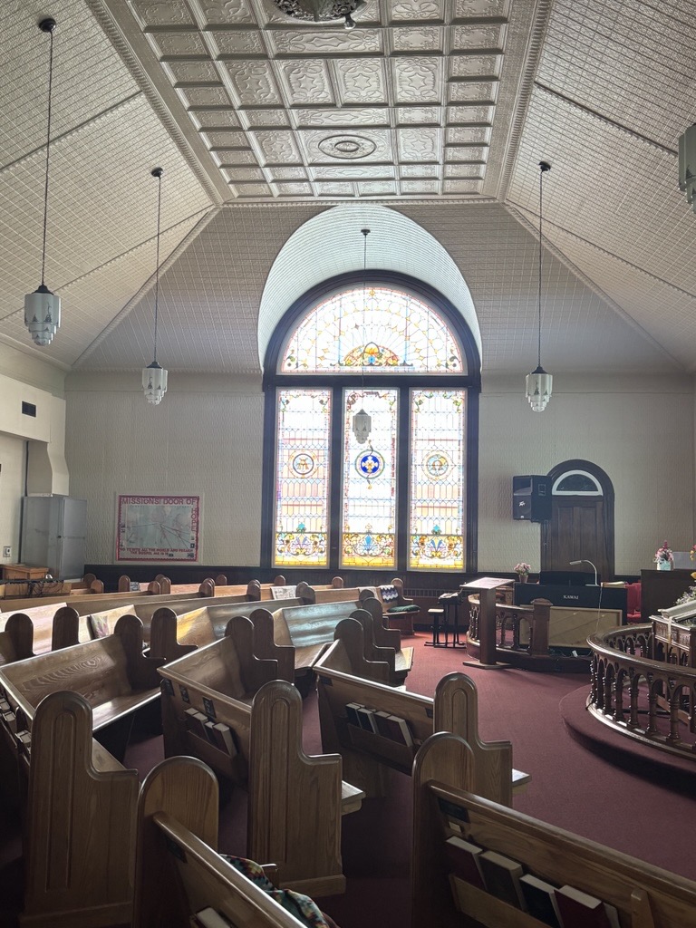 pews in a church sanctuary, with a large window in the background